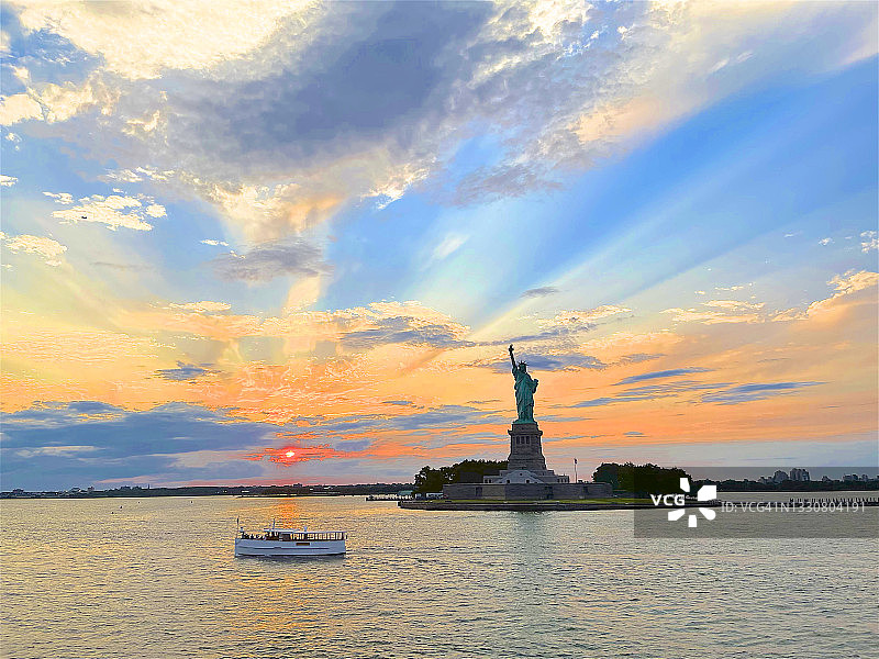黄昏时自由女神像附近的游船，纽约市图片素材