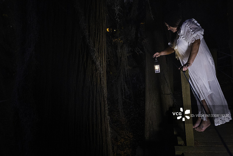 穿着睡衣的女人在夜晚探索沼泽图片素材