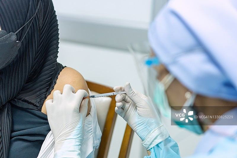 女护士在医院病房里为女患者接种新冠疫苗图片素材
