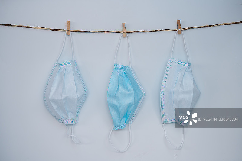 蓝色医用口罩挂在白色背景的晾衣绳上图片素材