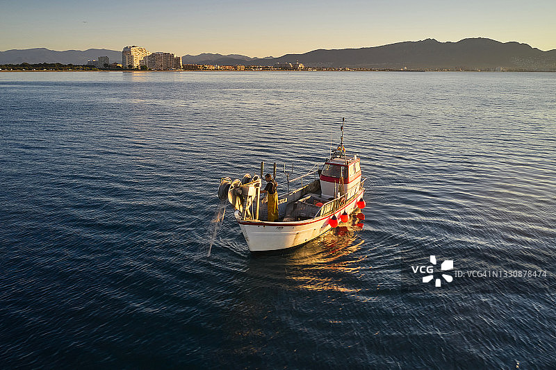 在船上用绞车整理渔网的渔民图片素材