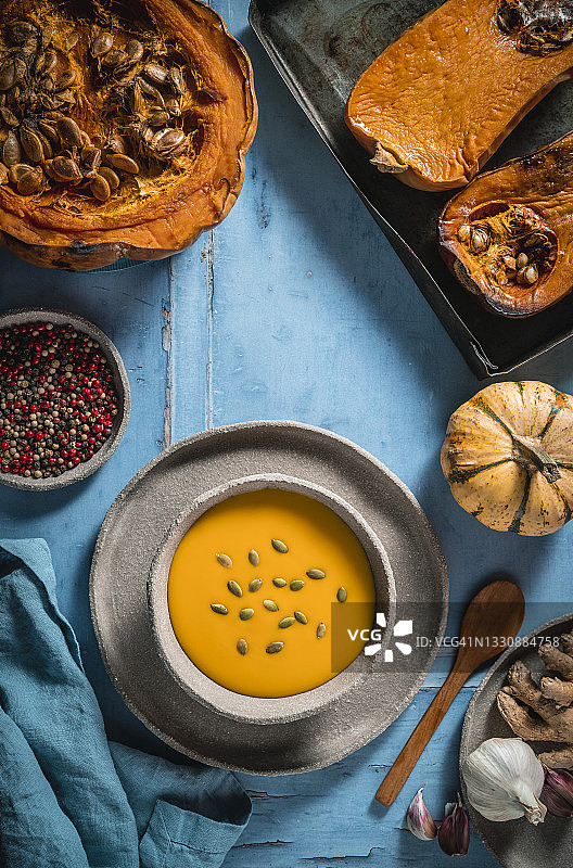 南瓜汤：蓝色餐桌上的姜蒜胡椒图片素材