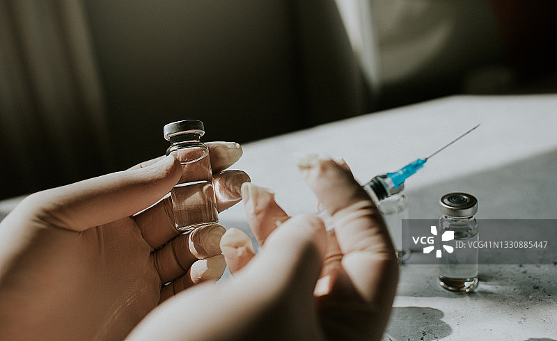 戴手套的手拿着注射器和药瓶——留白概念医疗图图片素材