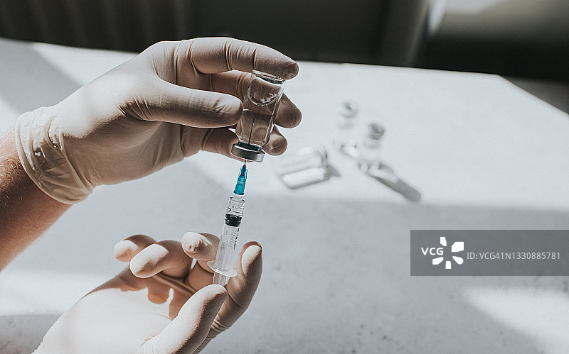 戴手套的手拿着注射器和药瓶——留白概念医疗图图片素材