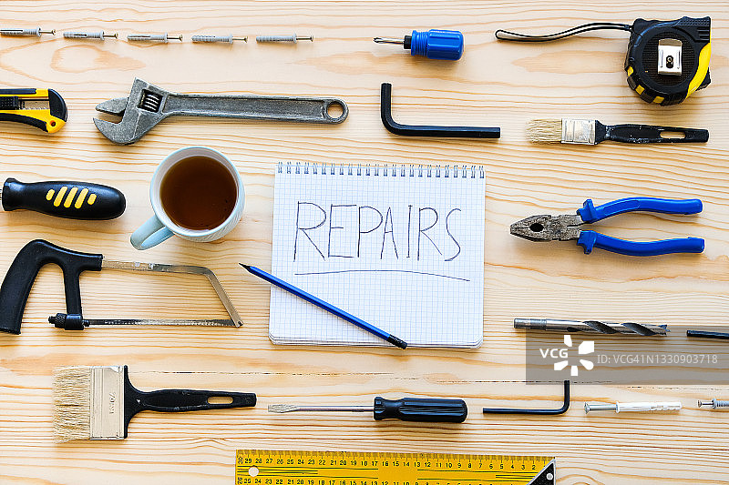 木桌上的笔记本、茶杯和房屋建造维修工具图片素材