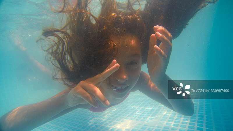 在室内游泳池水下玩耍的年轻女孩图片素材