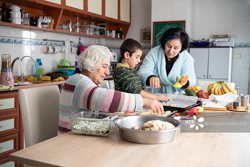 老年妇女、孙子和母亲在厨房做饭图片素材