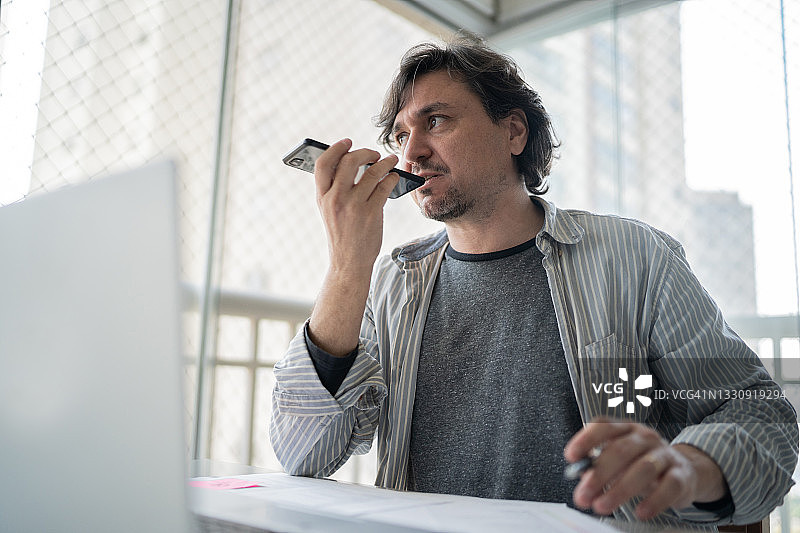 年长的男人在家用智能手机发送语音消息图片素材