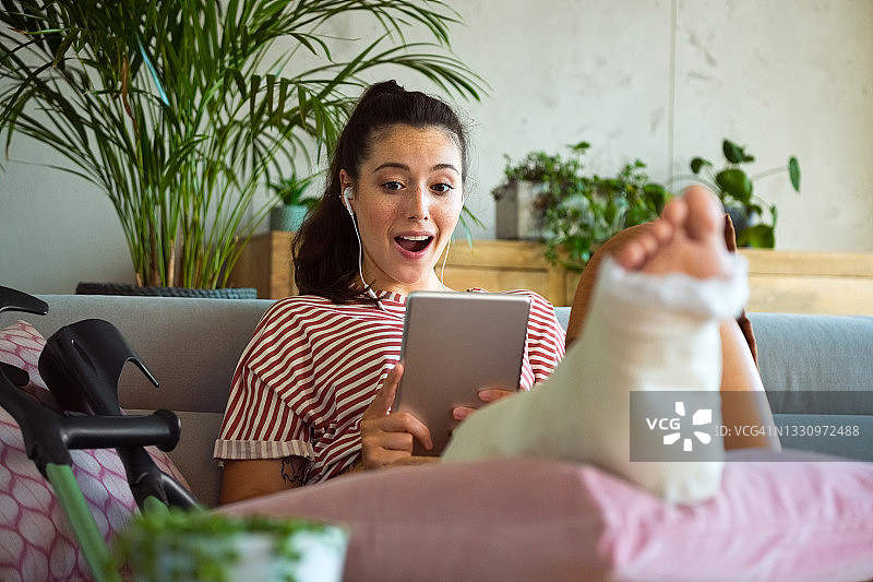 在家中腿部骨折的快乐年轻女人图片素材