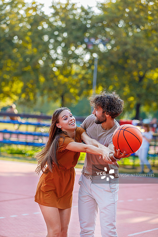 快乐的年轻情侣在大自然中打篮球图片素材