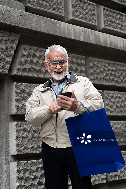 老年男人在市区行走并用手机发信息图片素材