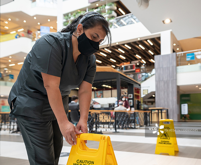 清洁女工戴口罩在购物中心拖地图片素材