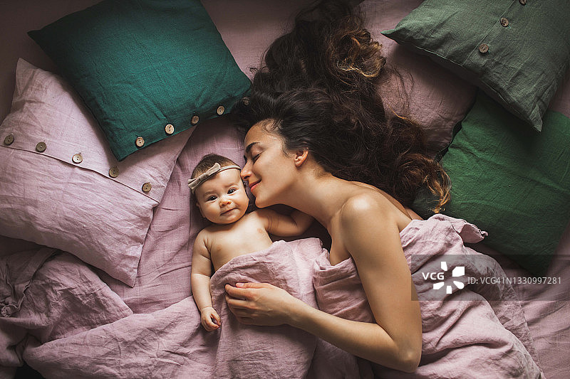 母亲和女儿在豪华床上依偎图片素材