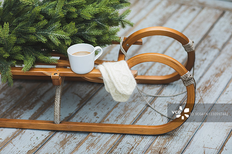 圣诞节期间，木制雪橇上放着热可可饮料和针织手套，旁边还有冷杉树图片素材