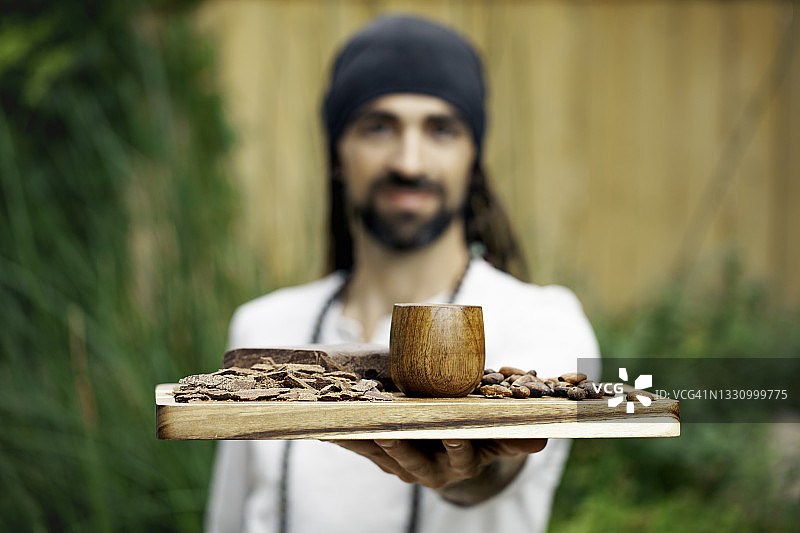 男人托着一盘仪式用可可豆酱和豆子图片素材
