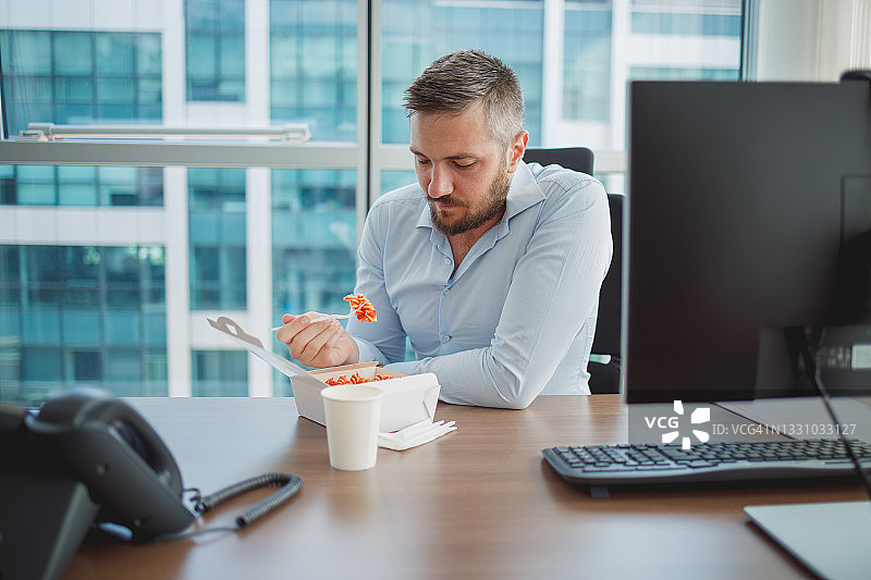 在办公室办公桌旁吃外卖午餐的商人图片素材