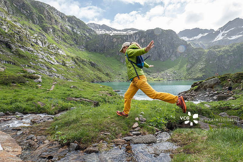 女性徒步旅行者跳过山涧，低角度拍摄图片素材