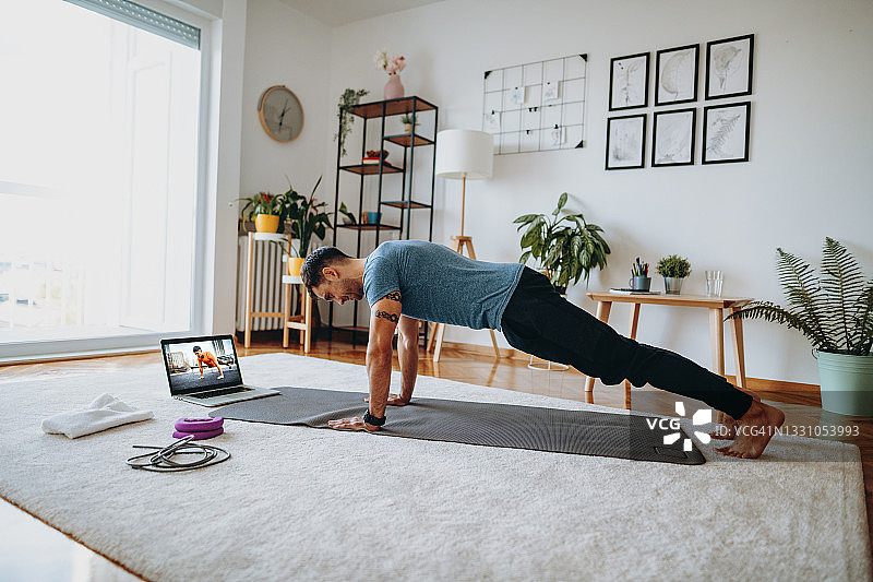 在教练的在线指导下做俯卧撑的男人图片素材