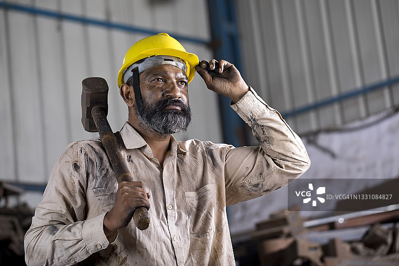 在工厂工作时拿着锤子的产业工人图片素材