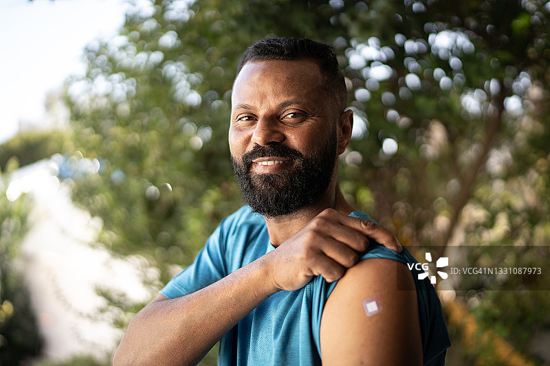 接种疫苗后展示手臂的快乐中年男人图片素材