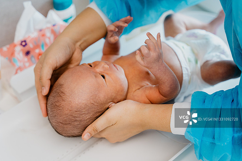 医生在诊所给新生婴儿称重图片素材