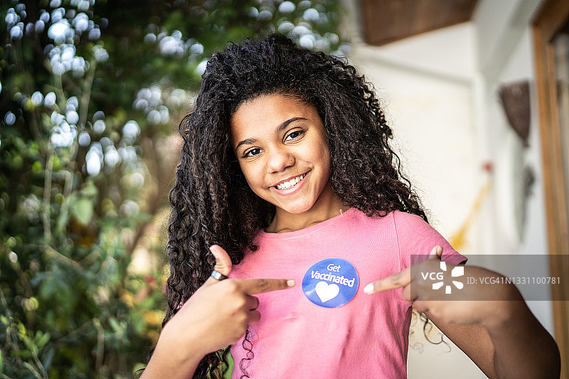 女孩展示衣服上的“已接种疫苗”贴纸图片素材