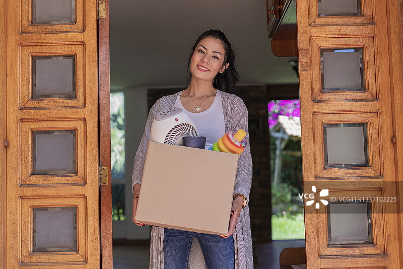 年轻女子搬新家，喜笑颜开地搬运行李图片素材