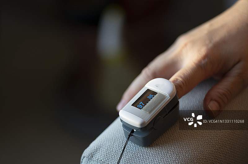 亚洲中年女性使用血氧仪测量血氧饱和度图片素材