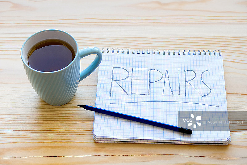 木桌上带有“维修”字样的笔记本和咖啡图片素材