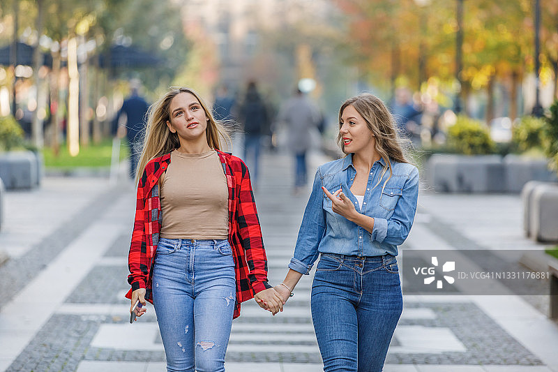 走在城市街区享受友谊的两个年轻女人图片素材