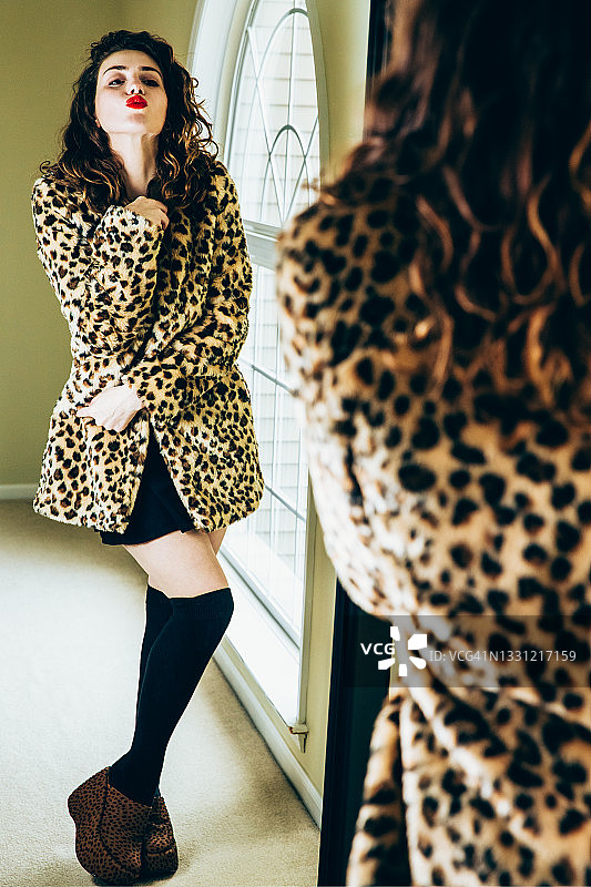 自信的女人照着镜子，穿着豹纹夹克嘟着嘴图片素材