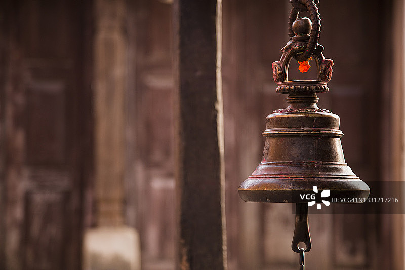 尼泊尔班迪普尔村一座小寺庙里黄铜钟的特写。棕色模糊背景。图片素材