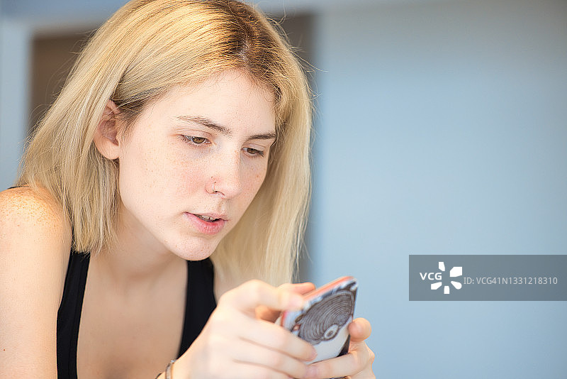 在家使用智能手机的金发女孩图片素材