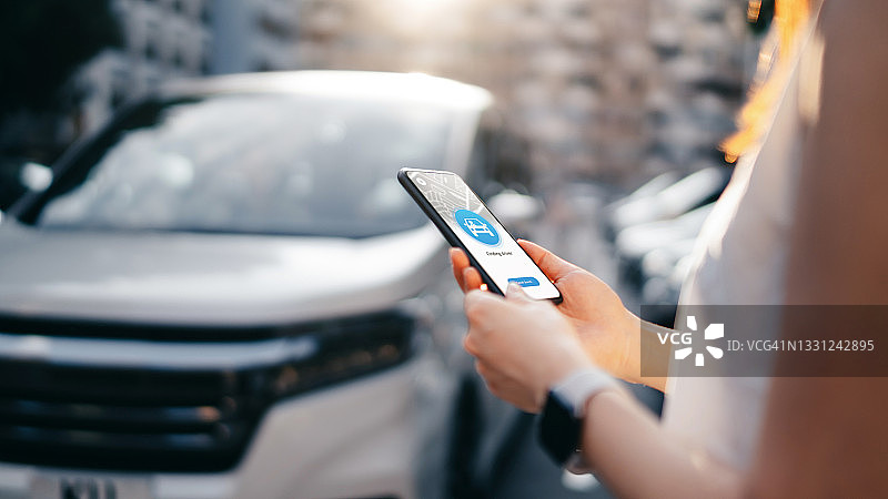 年轻女子在市中心街道使用手机应用程序安排专车接送服务图片素材