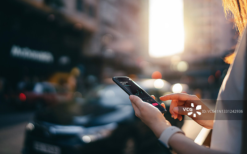 年轻女子在市中心街道的智能手机上阅读金融交易数据图片素材