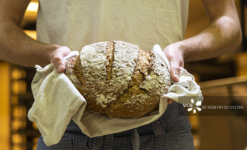 手持新鲜热面包的面包师图片素材
