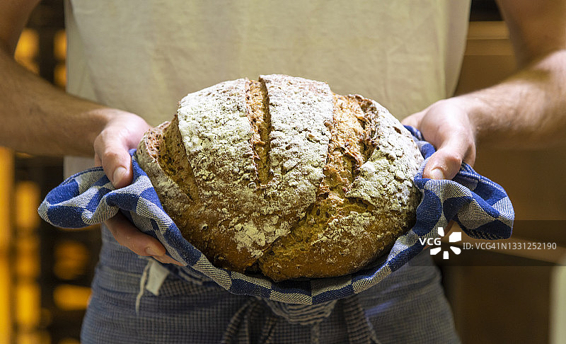 手持新鲜热面包的面包师图片素材