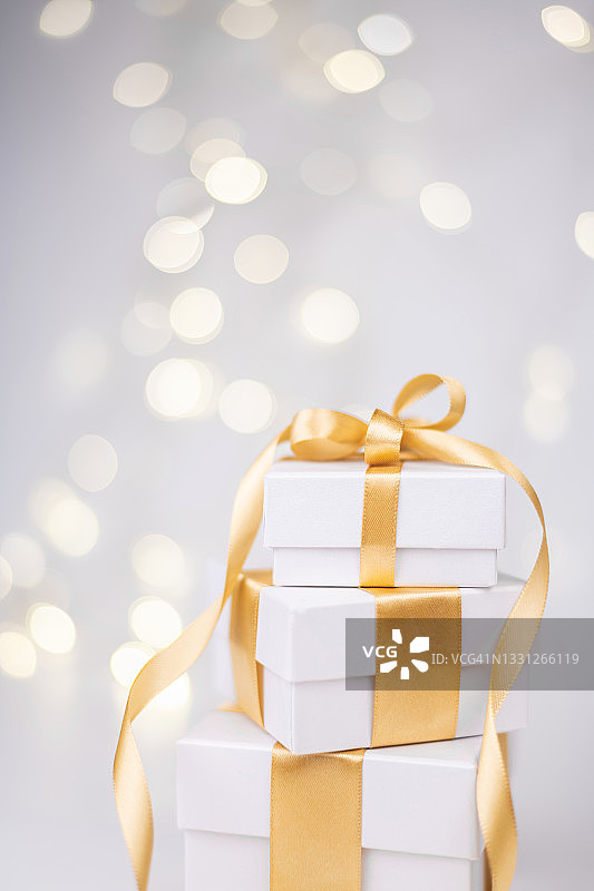 散景背景上的白色礼品盒与金色丝带图片素材