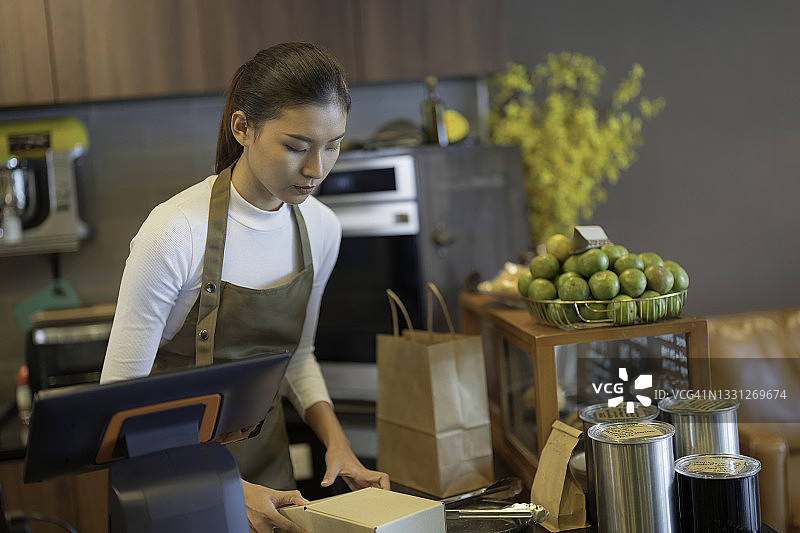 女服务员将顾客订单打包到纸袋中，准备顾客自提和外卖服务图片素材