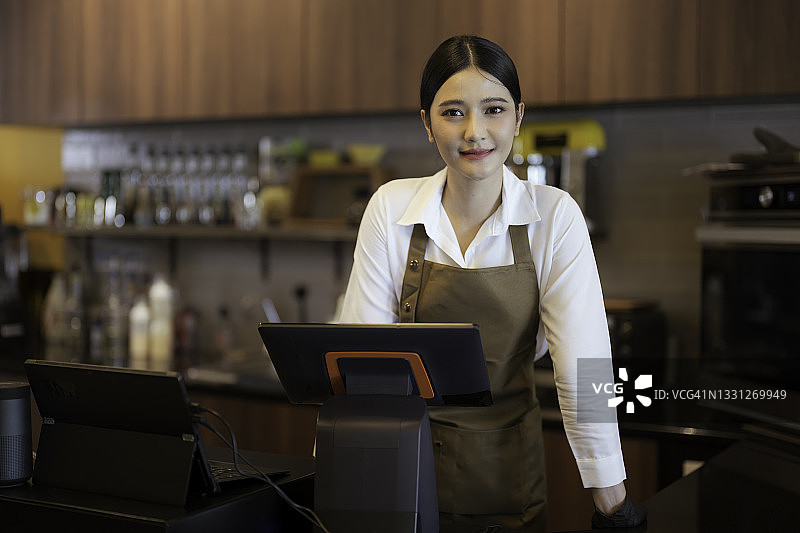 年轻的咖啡店老板站在吧台后欢迎顾客图片素材