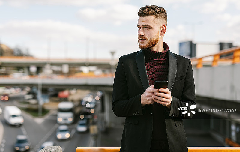 使用手机看向远方的英俊红发男子图片素材