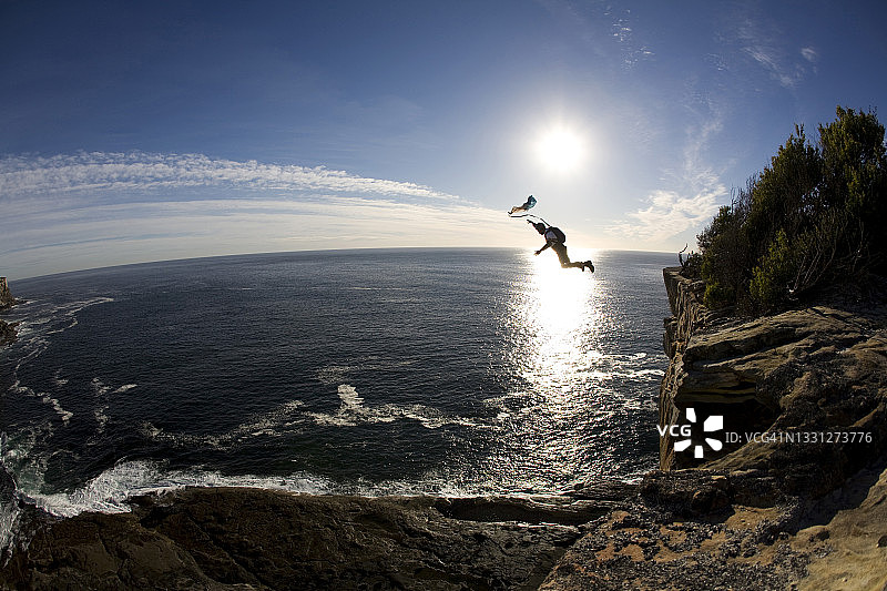 在澳大利亚新南威尔士州悉尼，定点跳伞者从悬崖上跳入大海图片素材