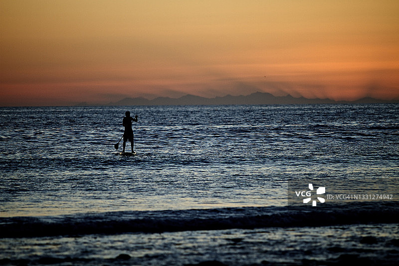 一名男子在墨西哥下加利福尼亚州享受着傍晚的桨板运动（剪影）图片素材