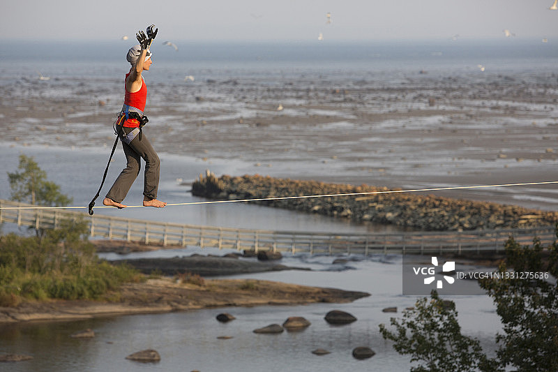 女性走绳者在朗格里夫的高空绳索上行走，背景是圣劳伦斯河图片素材