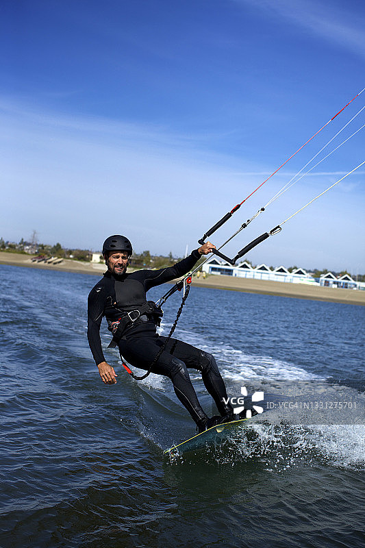 在加利福尼亚州圣地亚哥的任务湾，一位40岁左右的男性风筝冲浪者在风筝冲浪时看着镜头图片素材