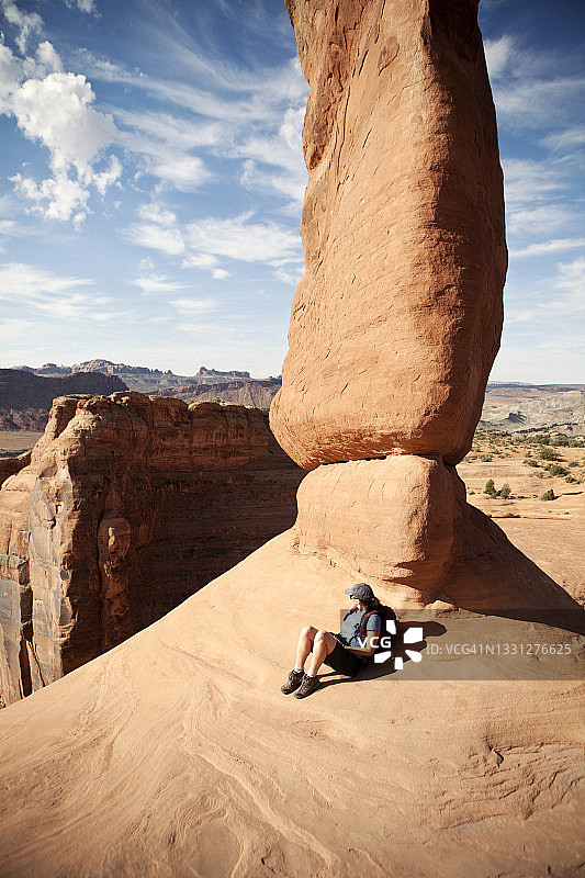 女徒步旅行者在美国犹他州拱门国家公园的精致拱门旁休息图片素材
