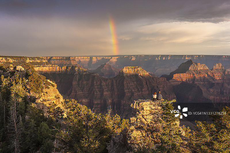 情侣坐着欣赏彩虹和大峡谷风光图片素材