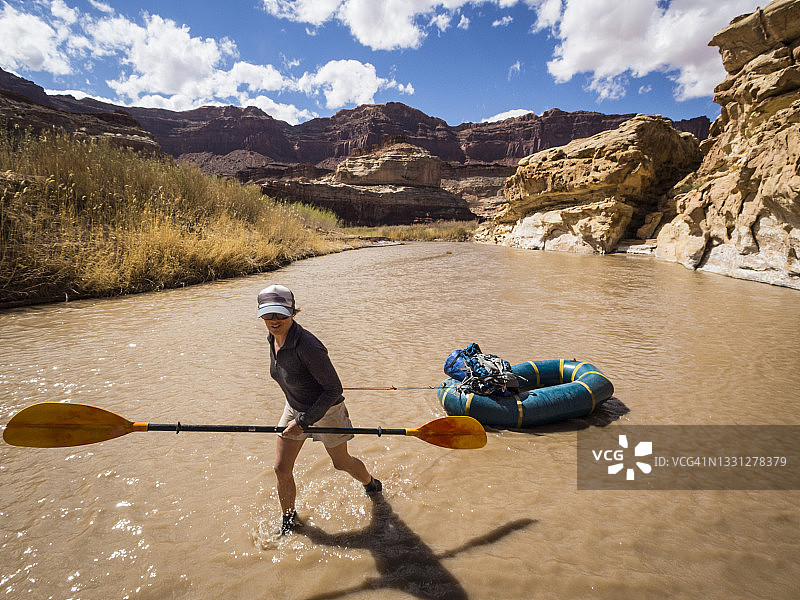 女子在浅水中拖着皮筏艇顺流而下图片素材