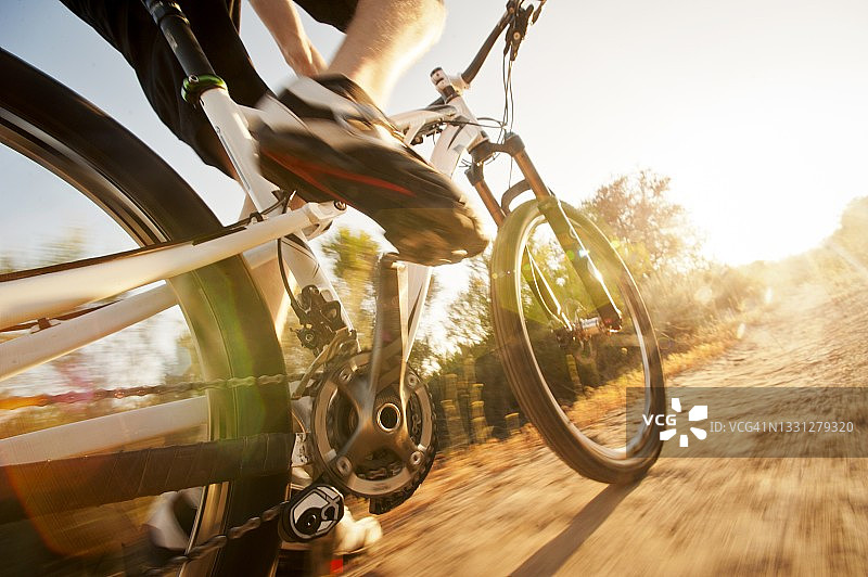 一个男人在泥泞小路上骑山地自行车的独特角度，这张照片给人一种速度感和动感图片素材