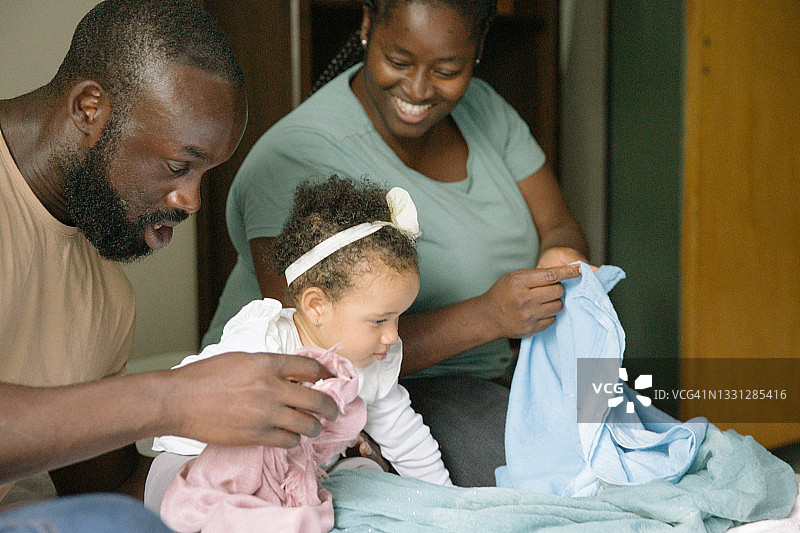 父亲陪女儿玩耍，母亲做家务的日常生活图片素材